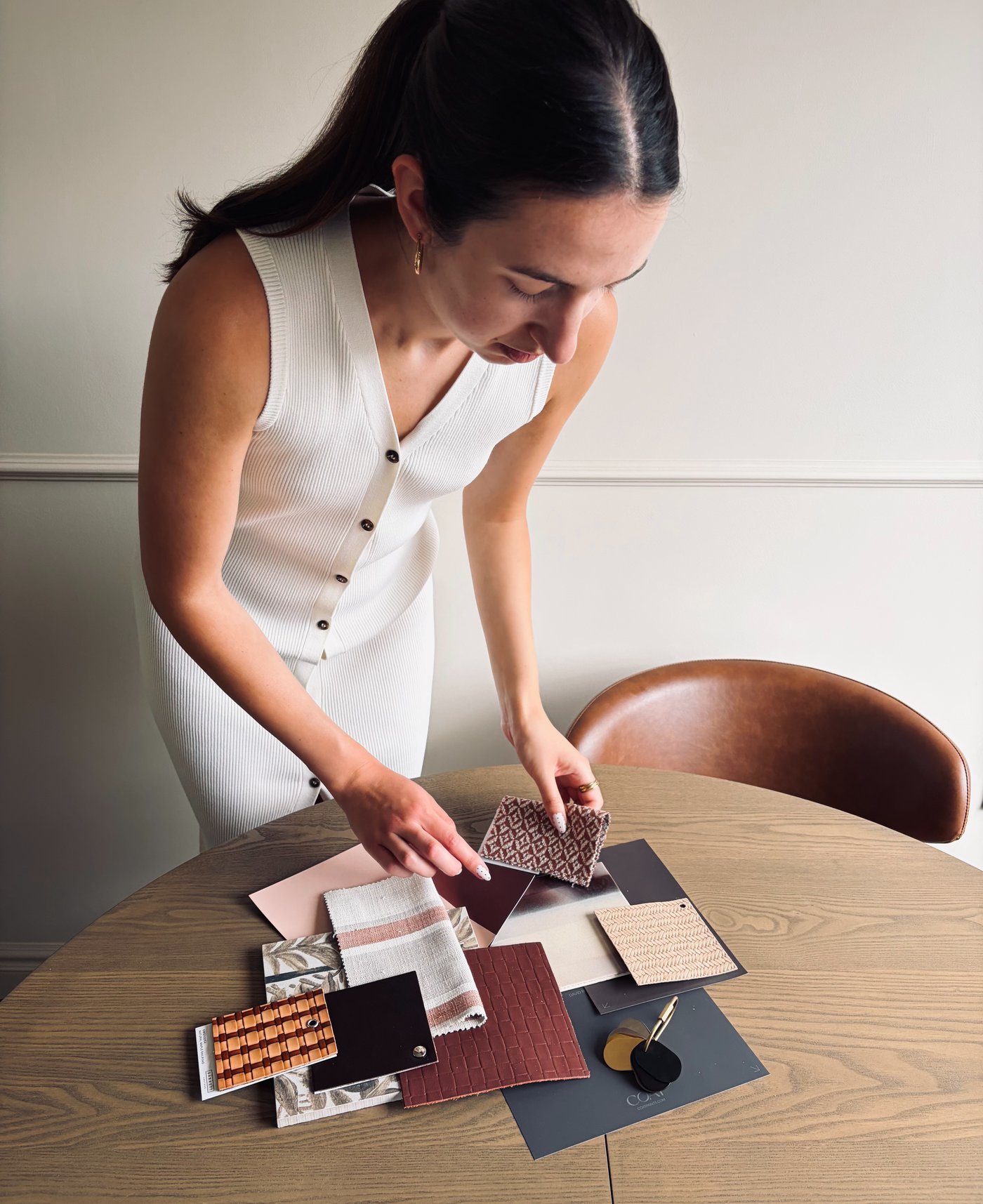 Emma, founder of Studio Epicoco, reviewing fabric and material swatches at a wooden table
